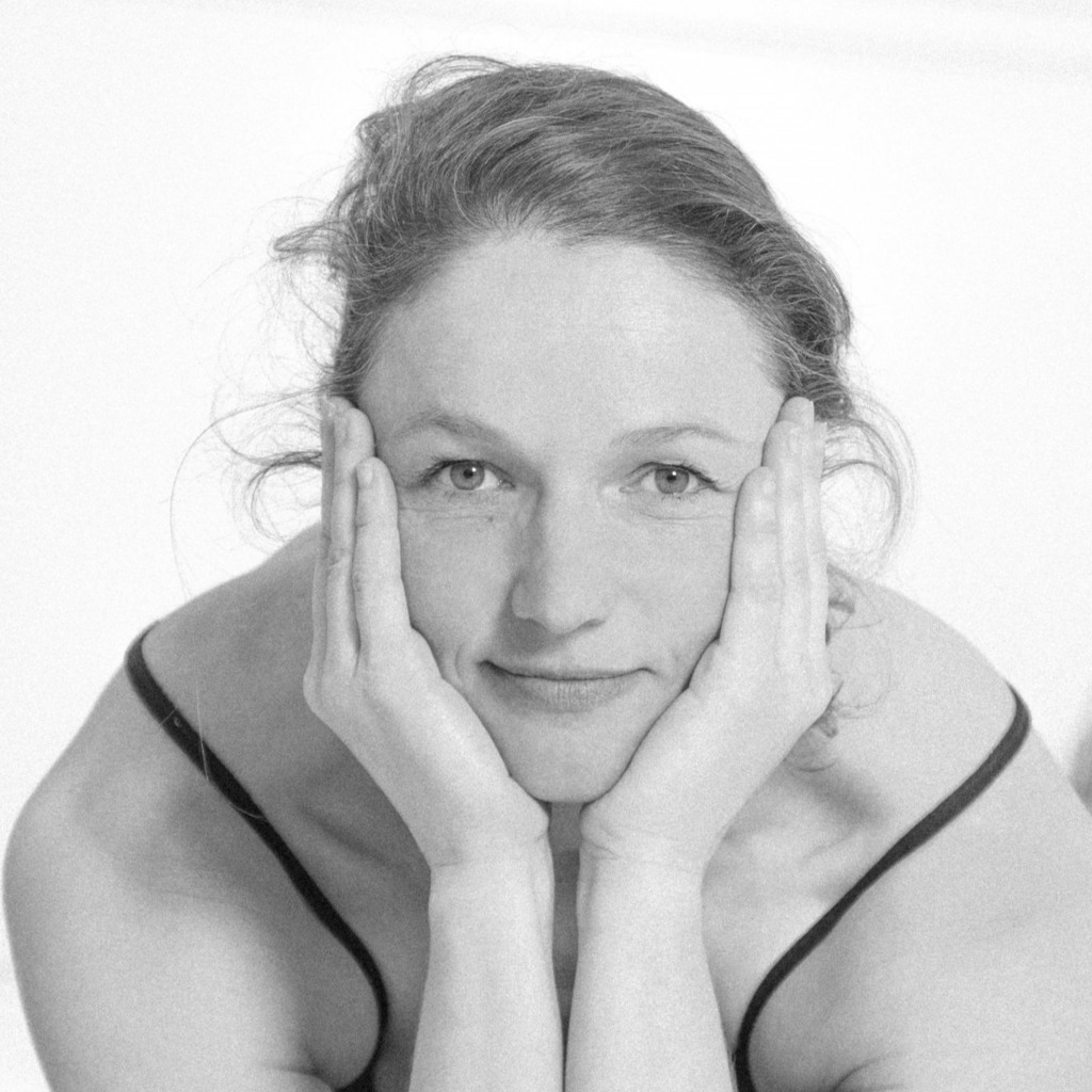 Laëtitia Lecuyer, paisible et souriante, en tenue de yoga, tenant sa tête dans ses mains. Photo en noir et blanc